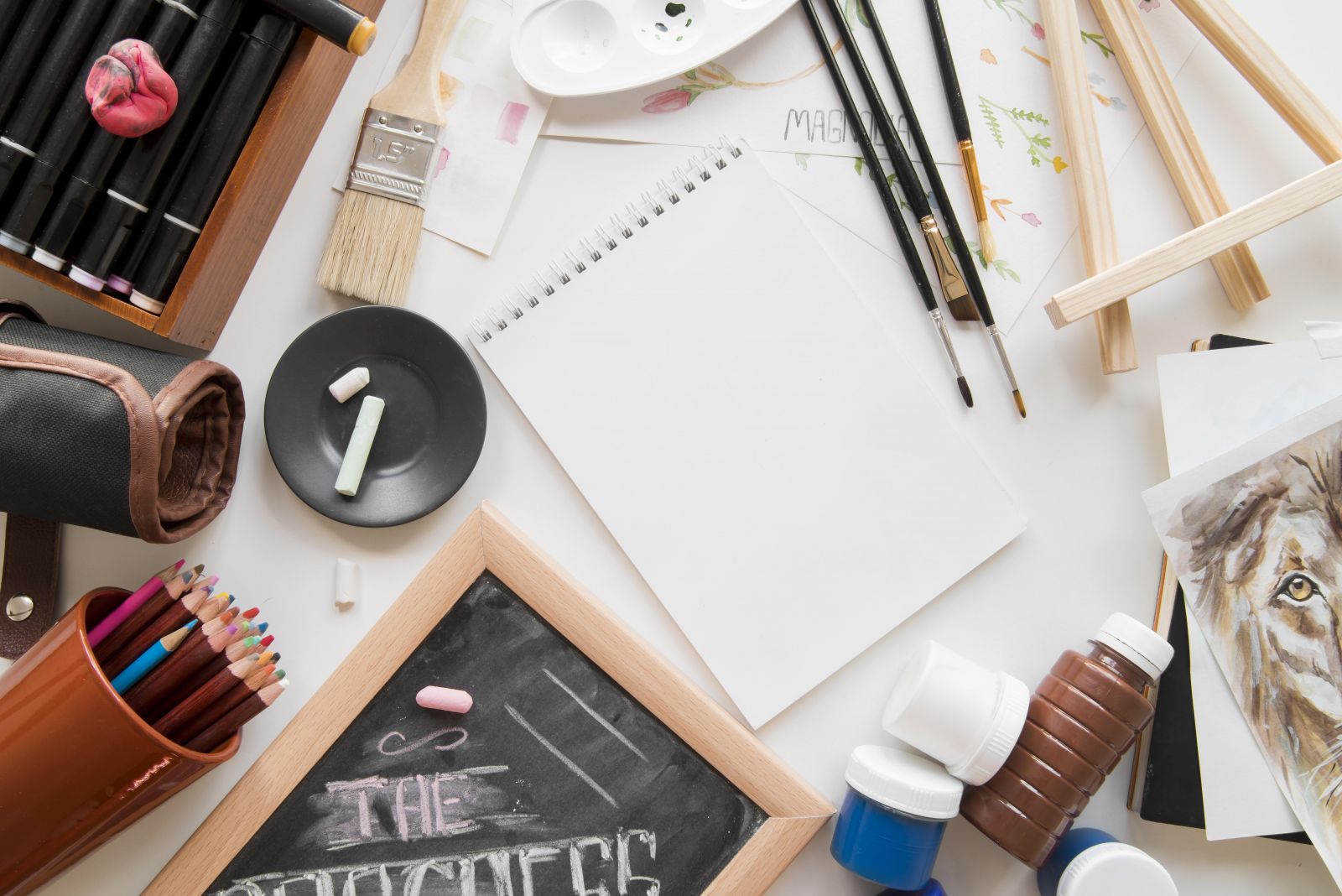 國外藝術升學作品集準備情境圖，桌面擺放素描本、畫筆、顏料與藝術工具，象徵作品集規劃與創作判斷過程。